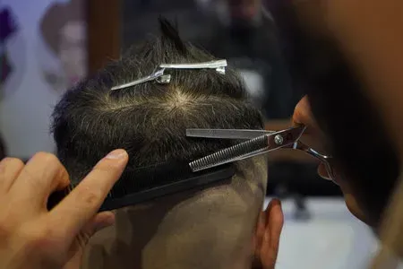 Corte de cabello con máquina en la nuca de un cliente.